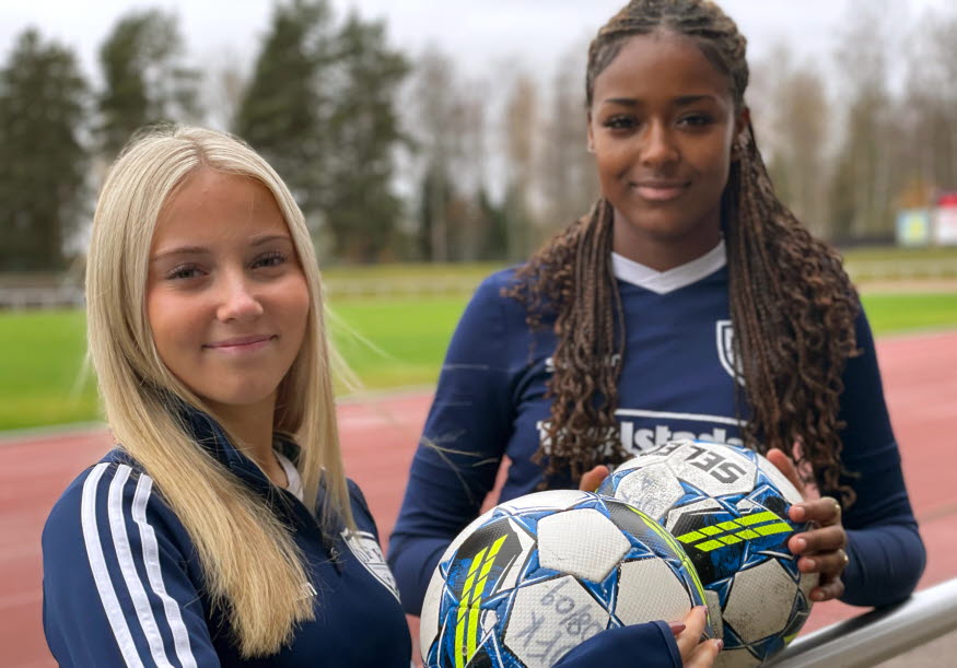 Två personer håller i varsin fotboll. 