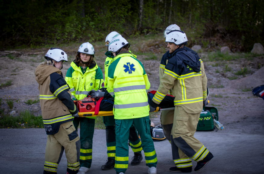 MBU-deltagare, både ambulanspersonal och räddningstjänst, bär en människa som ligger på en bår.