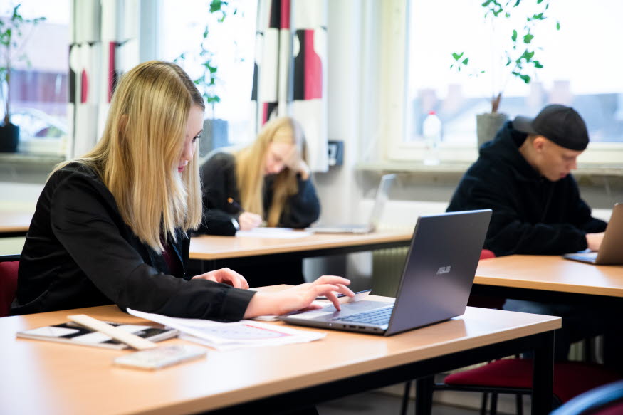 Tre elever i ett klassrum.