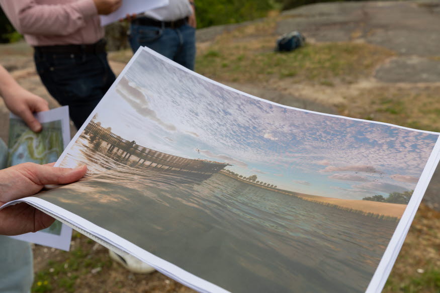 En person håller i en bild med vy över det nya gömslet som kommer att vara i en av dammarna.