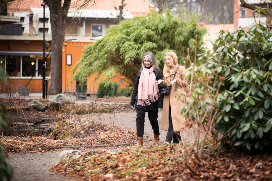 Två personer som pratar med varandra i en park. 