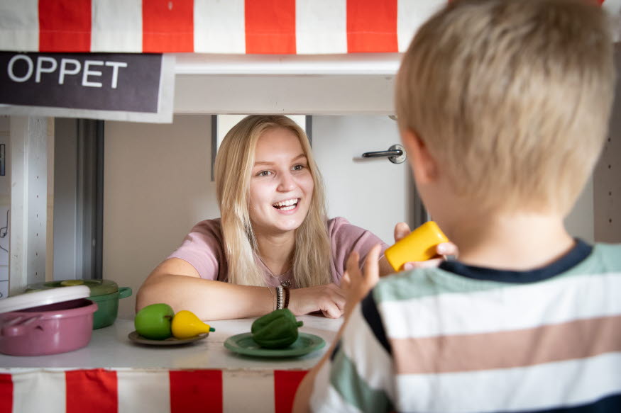 Elev som ler mot förskolebarn.