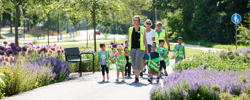 Förskollärare och barn promenerar bland blommor i Katrineholm. 