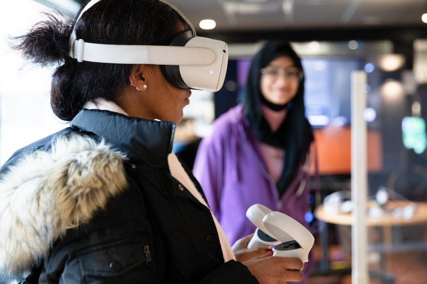 EN person med VR-glasögon och en person som tittar på. 