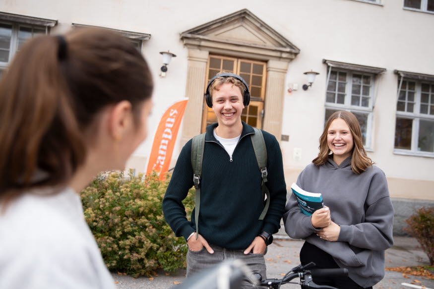 Två studenter utanför en vit byggnad. 