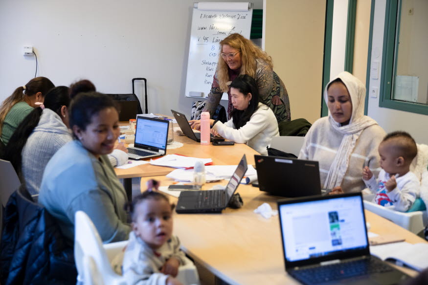 Mammor och små barn tillsamman med en lärare. 