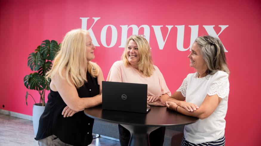 Tre kvinnor samtalar vid ett bord. 