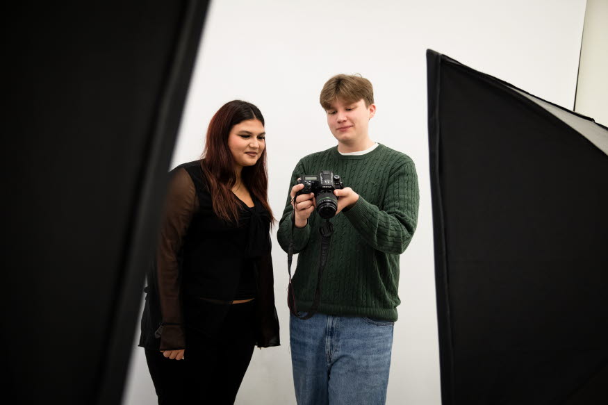 Två peroner tittar på bilder i en kamera. 