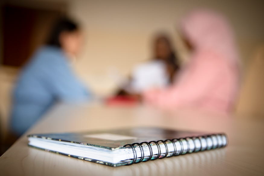 En bok med några elever i bakgrunden. 