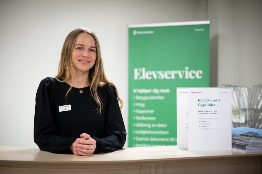 En person vid en reception. Bakom står texten Elevservice. 