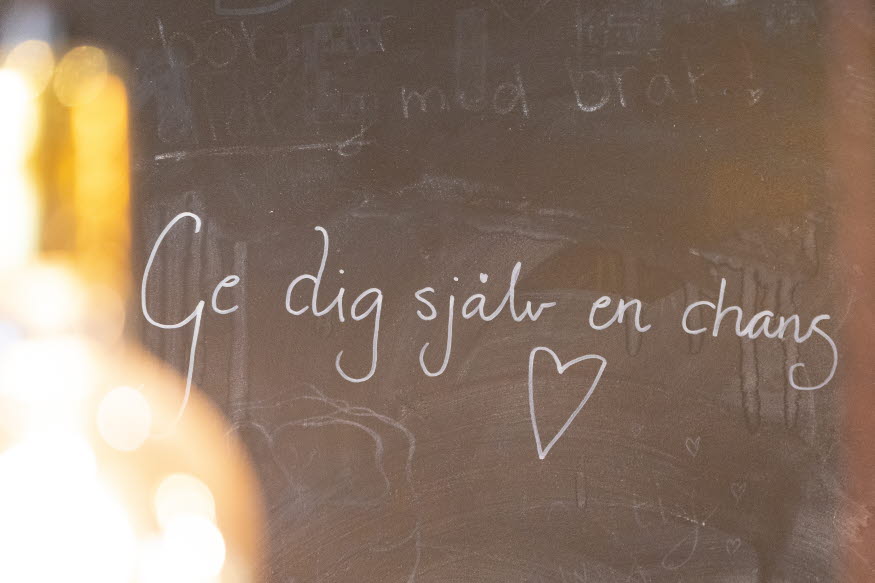 Text på svart vägg med krita: Ge dig själv en chans. Ett hjärta är ritat.