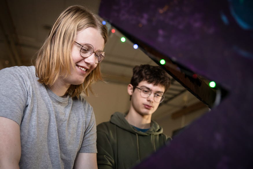 Två glada personer som arbetar koncentrerat vid en stor skärm. 