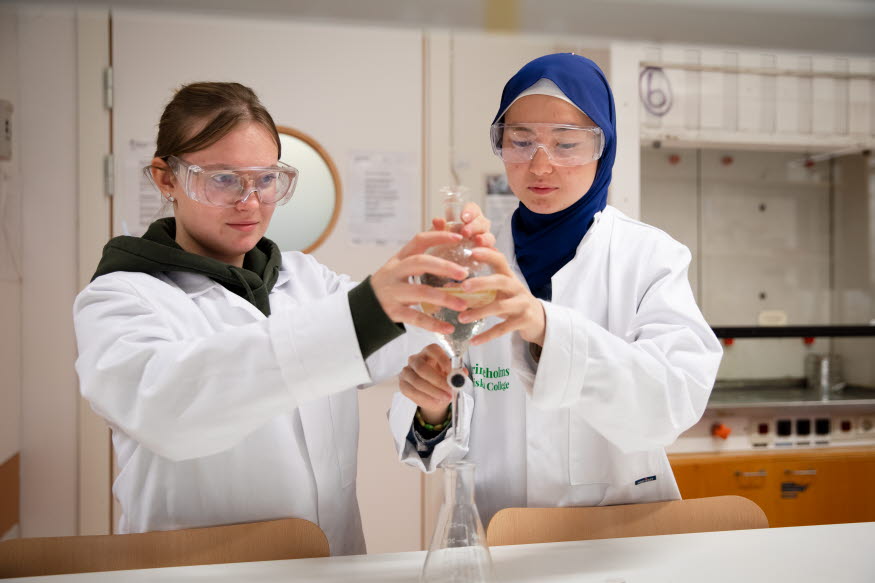 Elever i labbrockar gör ett experiment.