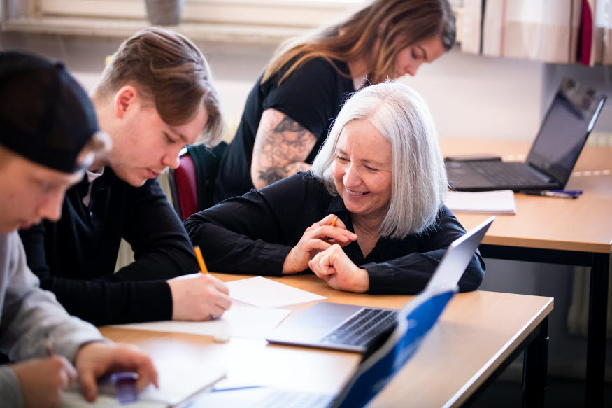 Några elever och en lärare i ett klassrum.