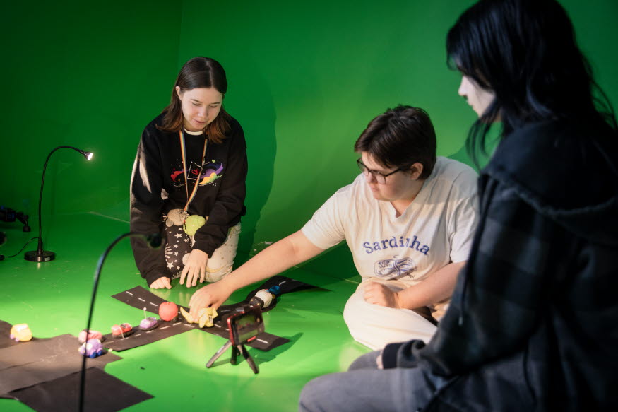 Tre personer som arbetar med att filma stop-motion med en mobiltelefon. 