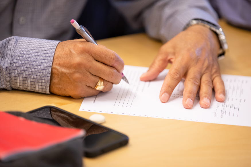 Händer som håller i papper och penna. 