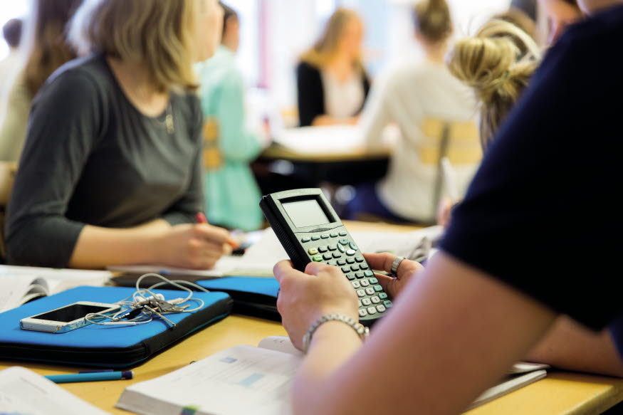 Elever i ett klassrum. En miniräknare i fokus.
