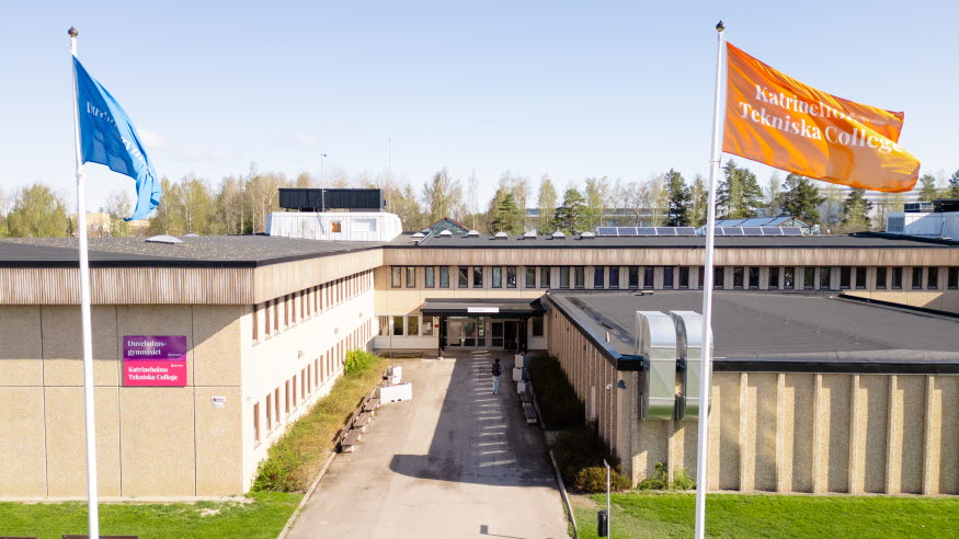 En beige betongbyggnad med två flaggstänger med flaggor i blått och orange. 