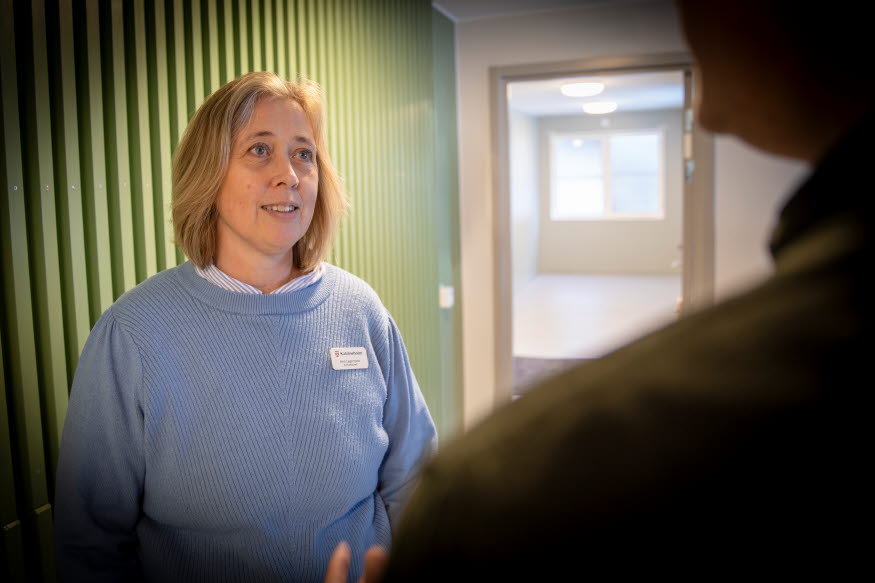 En kvinna med blå tröja har en konversation med en man. 