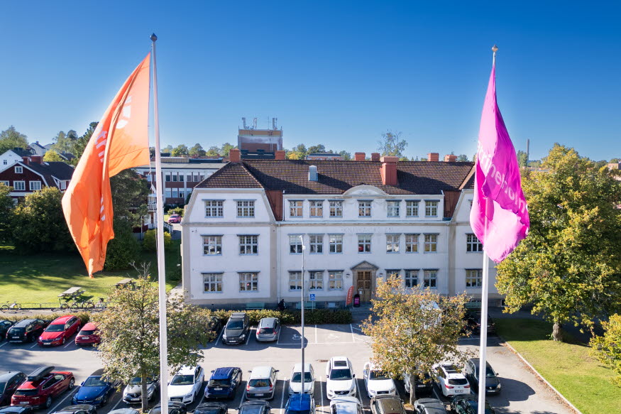 Stor vit byggnad med två flaggstänger framför. 