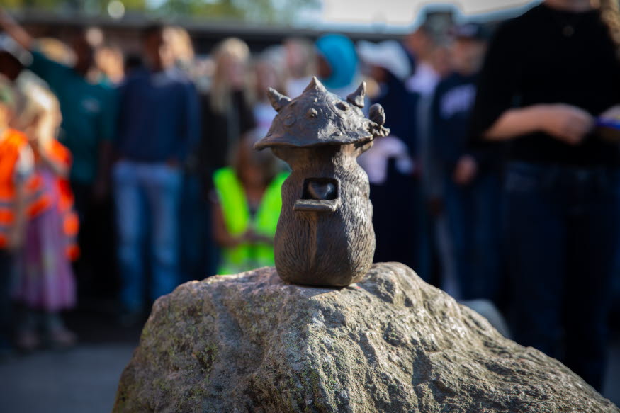 Näbbtrollet Mitzy som sitter på en sten, fotat bakifrån. På ryggen syns ett hjärta.